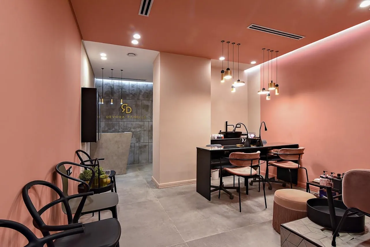 The nail bar and waiting area at Devora Ranells Beauty & Aesthetics Center, with blush-pink walls and gold pendant lights